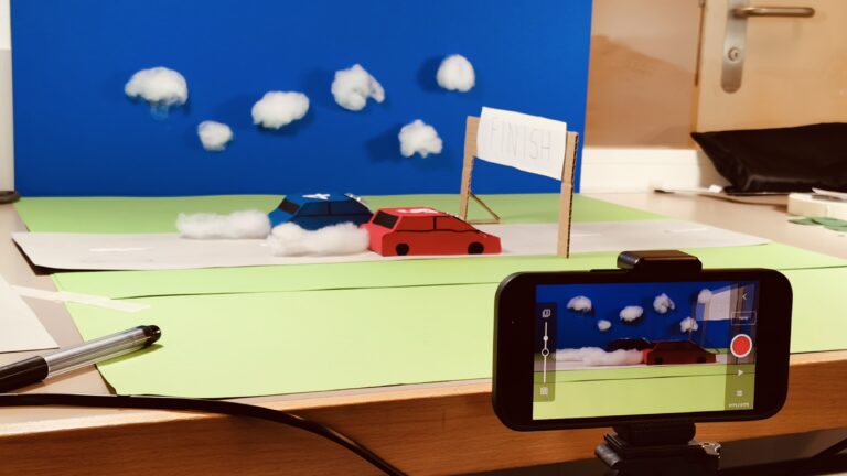 Teamevent Stop Motion Team Building. Szenerie mit Kamera und Rennautos aus Pappe.