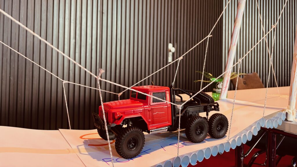 Teamevent Bridgemaker Brückenbau Team Building. Ferngesteuertes Auto auf Papierbrücke.